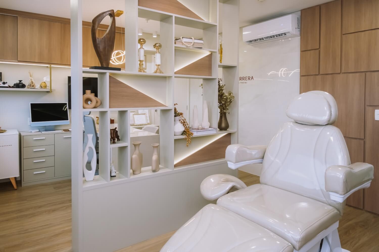 Consultório odontológico moderno com cadeira clínica branca e estante decorativa na Herrera Prime, dentista em São José dos Campos.
