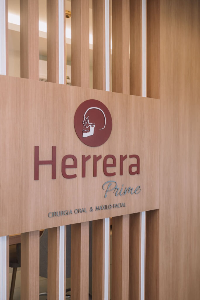 Logotipo da Herrera Prime em painel de madeira elegante na clínica odontológica em São José dos Campos com foco em cirurgia bucomaxilofacial.