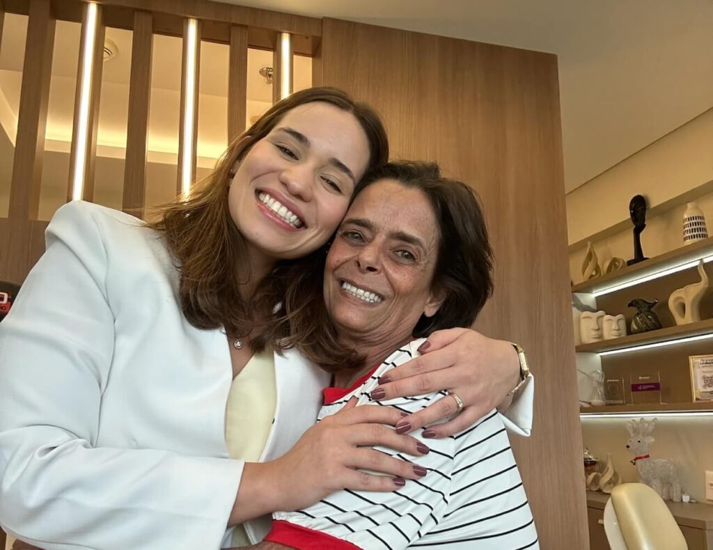 Dentista da clínica Herrera Prime abraça paciente feliz com seu novo sorriso após implante zigomático em São José dos Campos.