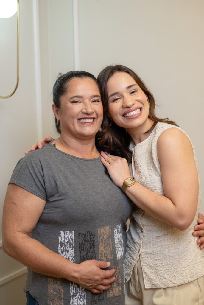 Dentista e paciente sorriem abraçadas celebrando o resultado final da prótese protocolo superior na Herrera Prime de São José dos Campos.