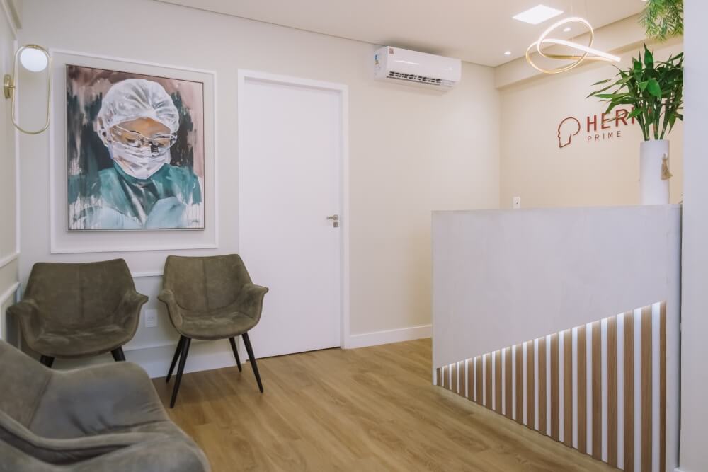 Recepção moderna com balcão de atendimento iluminado e quadro de cirurgiã na clínica odontológica em São José dos Campos Herrera Prime.