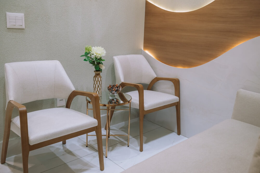 Sala de espera com poltronas confortáveis e mesa de centro com flores na clínica odontológica em São José dos Campos Herrera Prime.